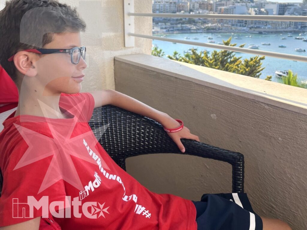 Uno studente adolescente si rilassa sul balcone guardando barche, mare ed edifici del porto durante la sua esperienza inMalta.