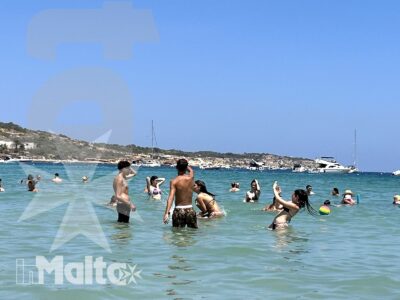 Gruppo di giovani fa il bagno nel mare turchese tra barche e costa maltese, durante un'uscita ricreativa inMalta.