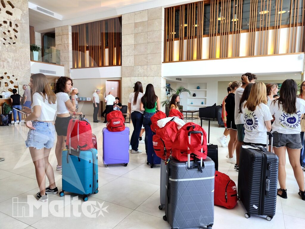Studenti con valigie e zaini riuniti nella hall moderna e luminosa del Salini Resort durante il soggiorno