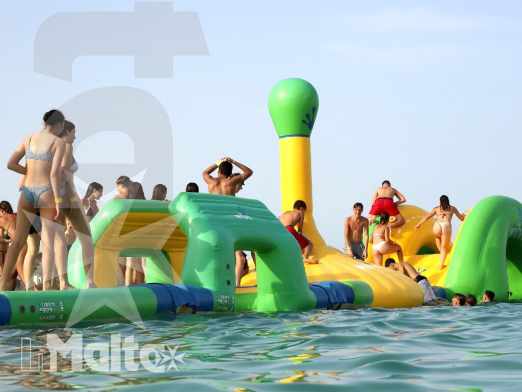 Studenti e studentesse inMalta affrontano insieme il percorso gonfiabile dei Water Games sul mare a Malta