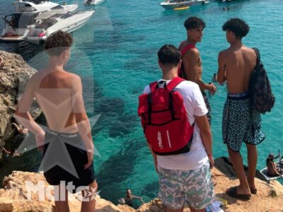 Gruppo di studenti osserva le barche in una baia rocciosa dalle acque turchesi durante l'escursione alla Blue Lagoon.