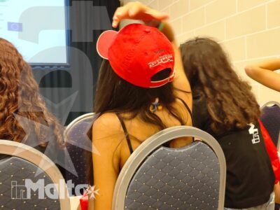 Studenti siedono in aula durante una lezione, rivolti verso uno schermo per proiezioni nel contesto di un soggiorno linguistico.