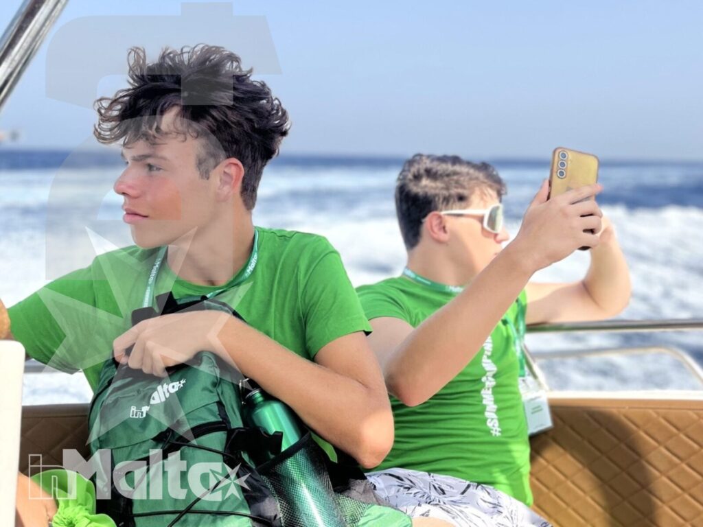 Uno studente fotografa le onde mentre un compagno osserva il mare dalla barca durante l'escursione.
