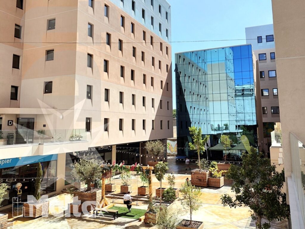 Cortile moderno per partecipanti alle vacanze studio Cortile moderno con aiuole, panchine, facciata vetrata e spazi commerciali, ambiente comune per partecipanti alle vacanze studio.