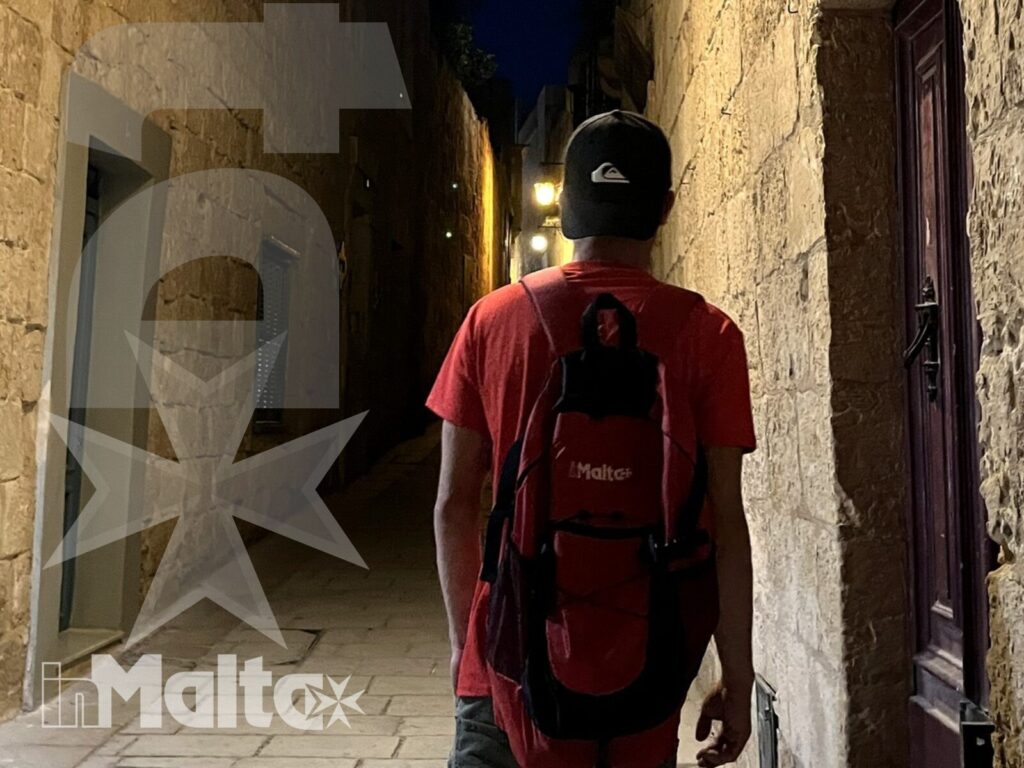 Studente inMalta esplora i vicoli serali di Mdina Studente con zaino cammina in un vicolo di Mdina illuminato dopo il tramonto, durante una passeggiata serale in Malta.