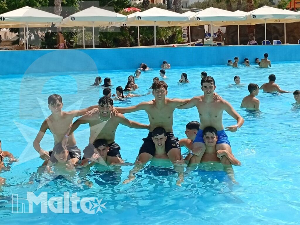 Studenti insieme in piscina durante una giornata di svago Un gruppo di studenti forma una piramide umana in piscina, condividendo un momento di gioco e socialità durante il soggiorno.