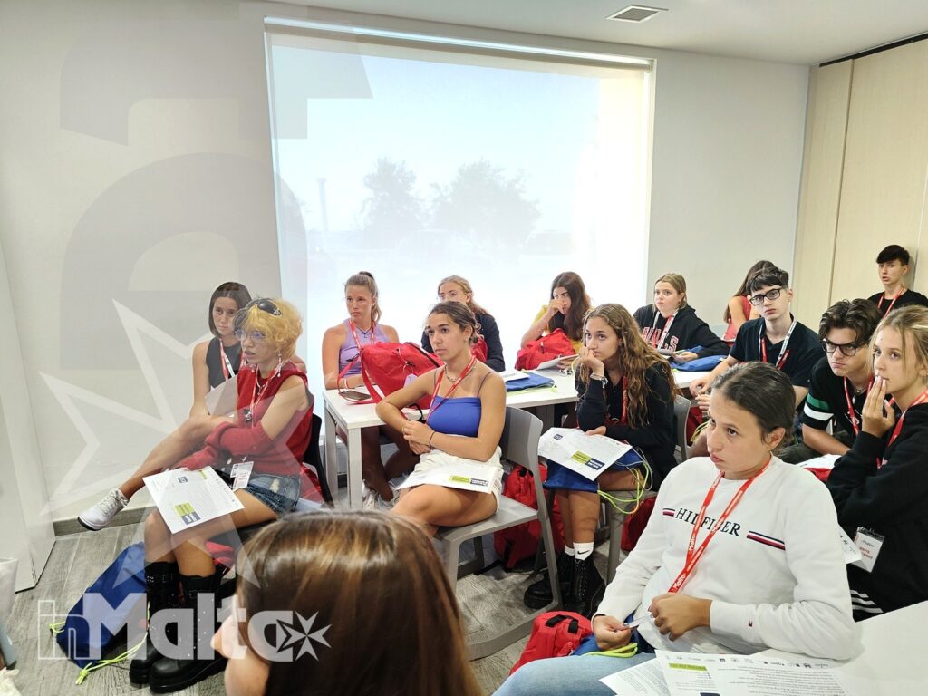 Studenti internazionali siedono ai banchi durante una lezione con proiettore e materiali didattici, nel contesto di una vacanza studio a Malta.