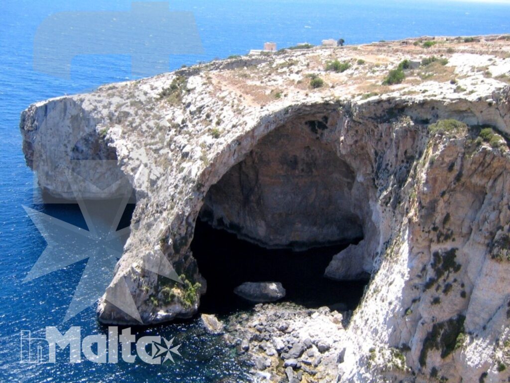 Arco naturale e grotta marina sulla costa di Malta Grande arco naturale e grotta marina si aprono nella scogliera chiara, sopra il mare blu intenso della costa maltese.