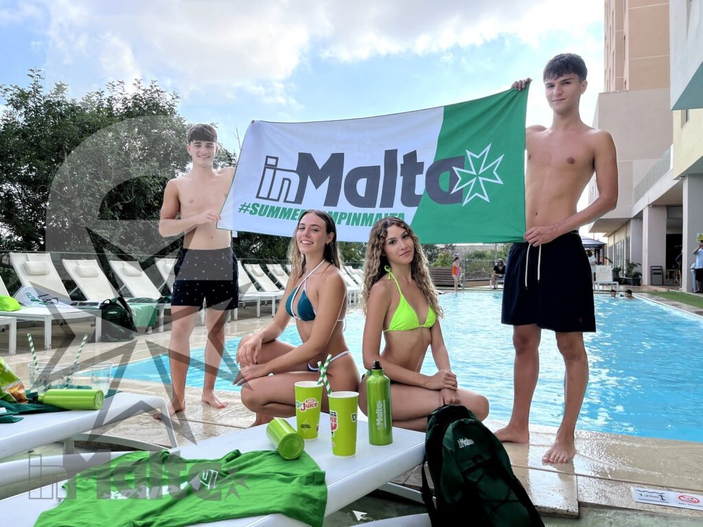 Gruppo di ragazzi a bordo piscina con banner inMalta