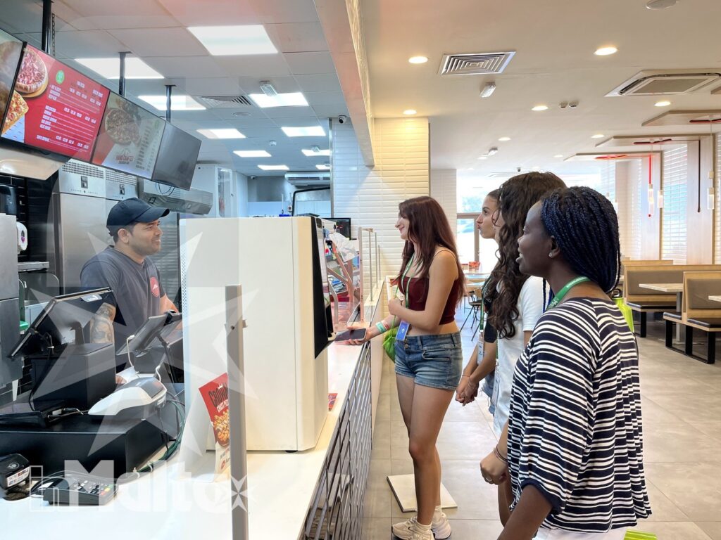 Studentesse internazionali ordinano insieme al banco di un ristorante durante il soggiorno studio a Malta.