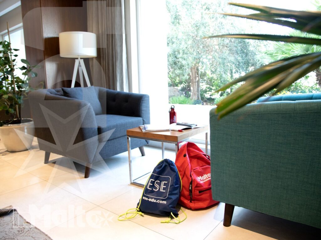 Salottino luminoso del Salini Resort con zaini identificativi degli studenti, poltrone, vetrata sul verde e spazio per il relax.