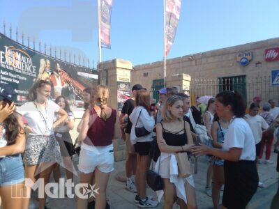 Gruppo di studenti con zaini conversa davanti a un ingresso turistico nel centro storico di Malta, durante una visita alla destinazione.