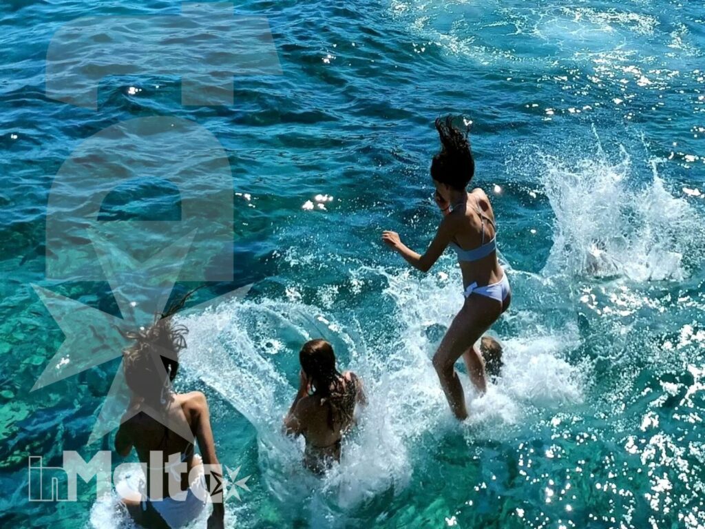Giovani in acqua durante l'attività al mare a Malta Gruppo di giovani salta e nuota in acque turchesi durante una giornata al mare a Malta, tra schizzi e atmosfera estiva.