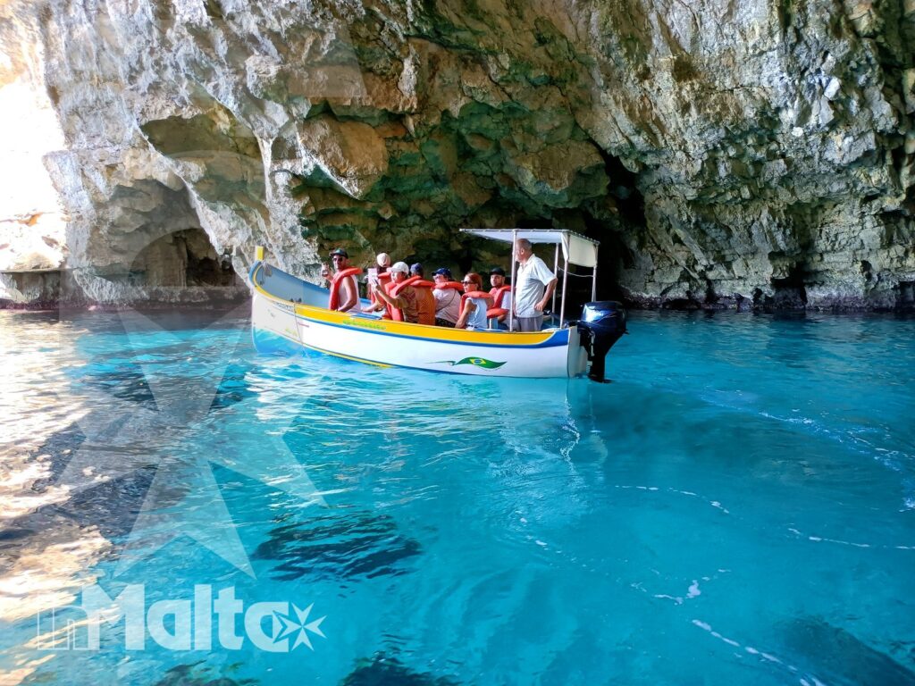 Escursione in barca nella grotta marina della Blue Grotto Barca con passeggeri entra in una grotta marina dalle acque turchesi durante un'escursione costiera alla Blue Grotto.