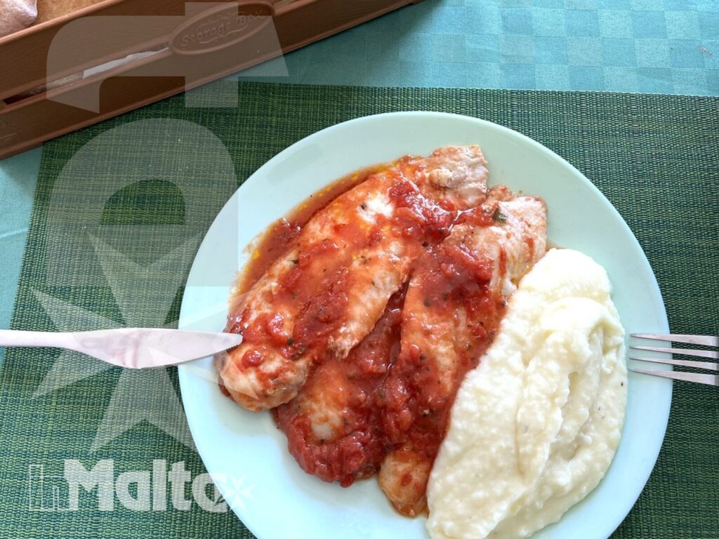 Pasto caldo con contorno cremoso, pane e posate, servito nella sala da pranzo durante un soggiorno studio a Malta.