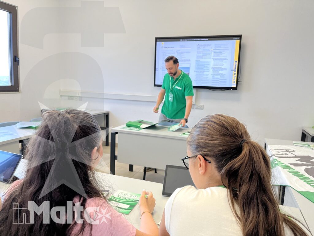 Lezione di lingua con studenti nella scuola di Malta Docente conduce una lezione davanti a studenti che ascoltano e prendono appunti, in un'aula luminosa della scuola di lingue.
