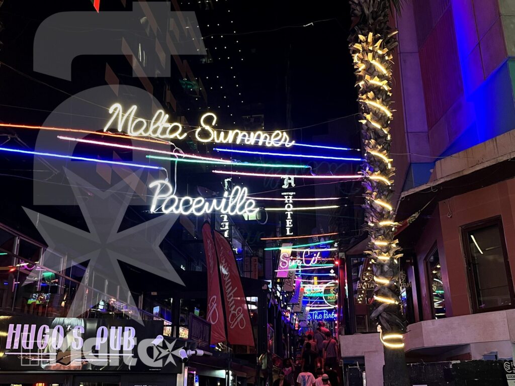 Paceville di notte tra pub, neon e palme illuminate Insegne al neon, pub, palma illuminata e locali affollati caratterizzano la vivace scena notturna di Paceville.
