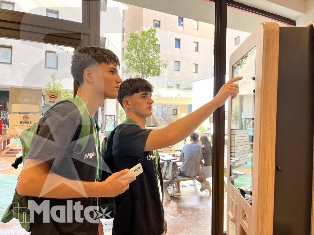 Due studenti leggono una mappa all'ingresso di una struttura, organizzando il proprio soggiorno linguistico a Malta.