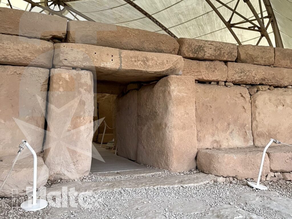 Ingresso megalitico di un antico tempio maltese Ingresso basso e profondo tra massicce pietre megalitiche, protetto da una moderna copertura durante la visita a un tempio maltese.