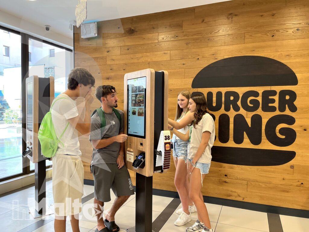 Gruppo di studenti internazionali ordina al kiosk di un Burger King maltese durante una giornata inMalta.