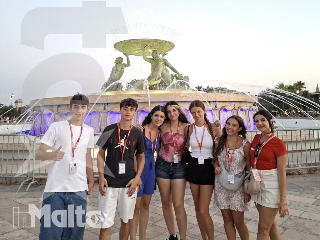 Studenti inMalta davanti alla fontana durante l'attività serale Sette studenti sorridono davanti a una fontana monumentale illuminata durante un'attività di gruppo a Malta