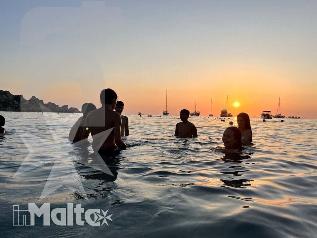 Corsisti inMalta fanno il bagno in mare davanti al tramonto maltese