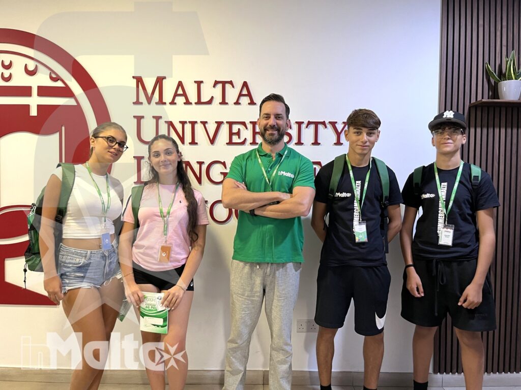 Studenti inMalta davanti alla Malta University Language School Gruppo di studenti e accompagnatore posa con badge all'interno della Malta University Language School durante un soggiorno formativo organizzato.
