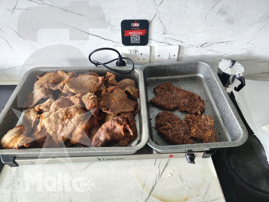 Due vassoi con preparazioni di carne impanata e arrosto pronti per il servizio al buffet dei partecipanti.