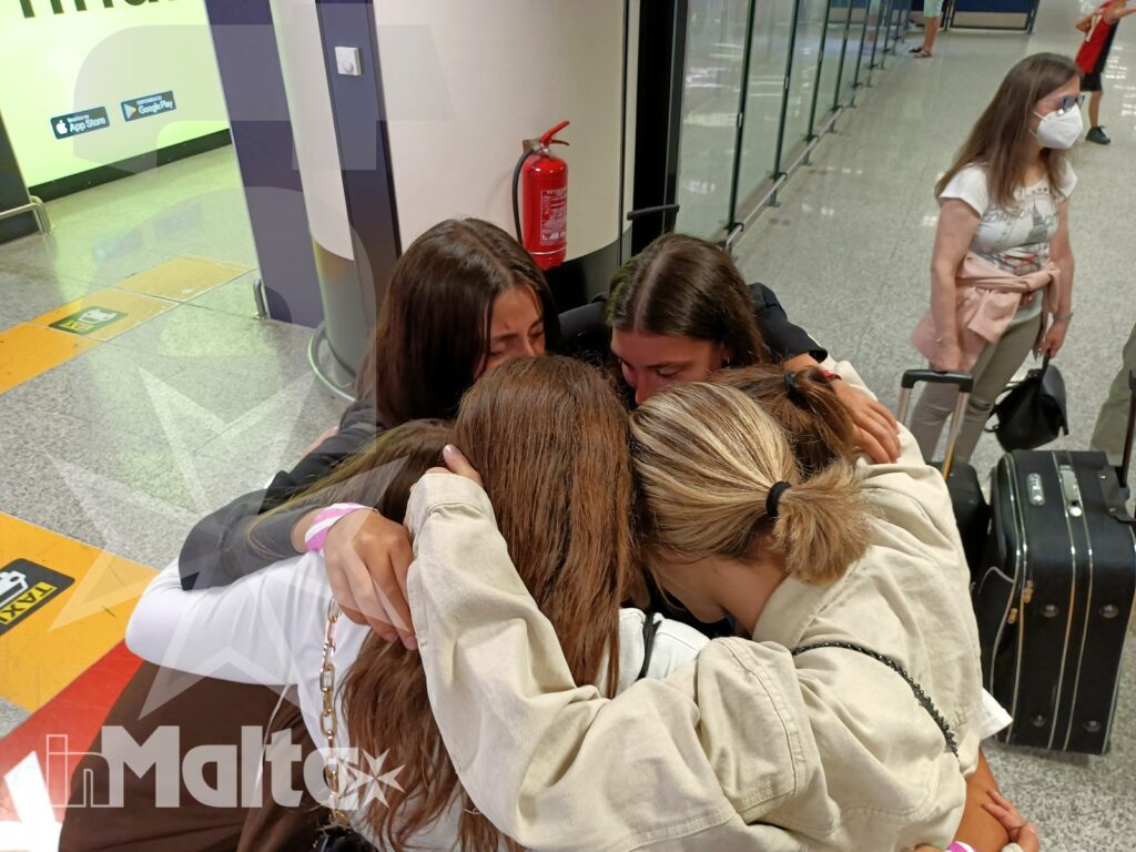 Studentesse inMalta si salutano prima della partenza Studentesse con le valigie si abbracciano nell'area partenze dell'aeroporto, esprimendo entusiasmo e amicizia all'inizio della vacanza studio.