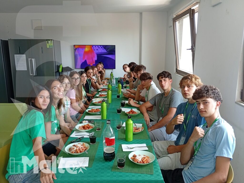Studenti siedono insieme a pranzo attorno a una tavola apparecchiata, vivendo un momento conviviale nel loro soggiorno studio.