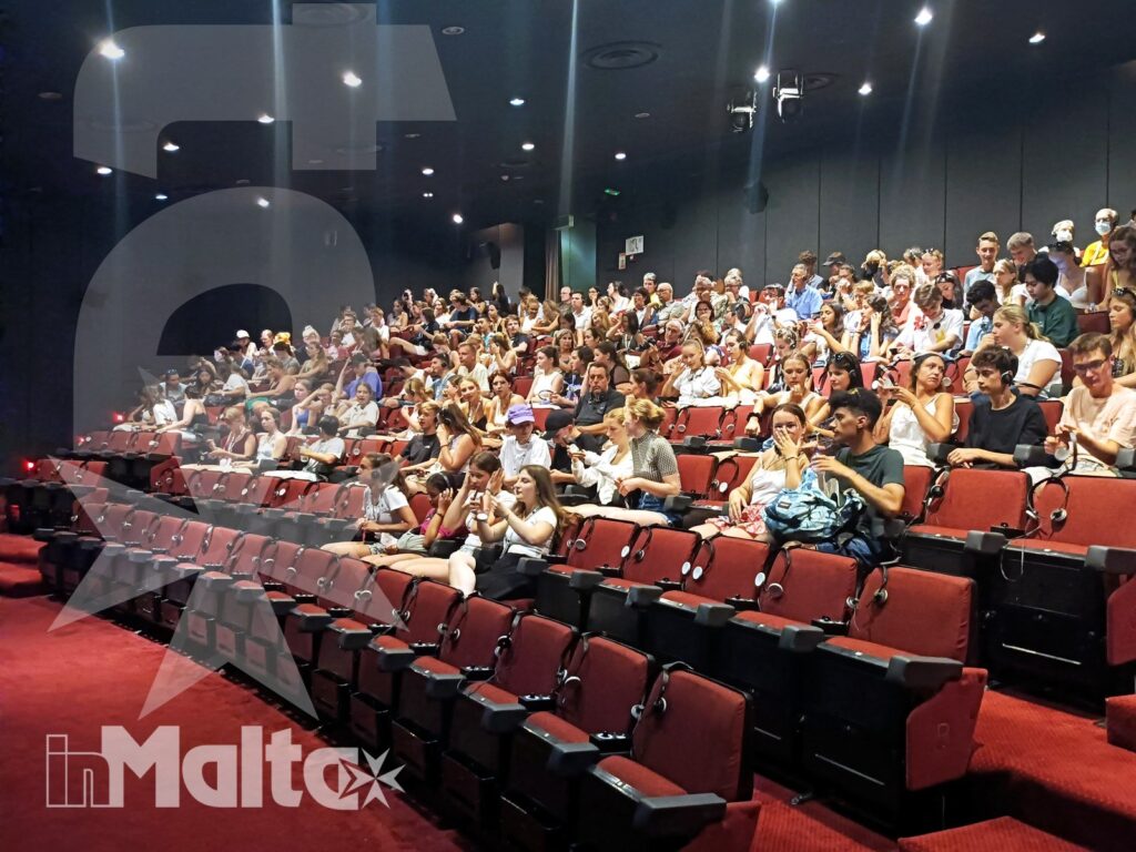 Partecipanti inMalta riuniti nell'auditorium per un'attività di gruppo Ampio gruppo di studenti siede sulle poltrone rosse a gradoni di un auditorium durante un'attività collettiva inMalta.