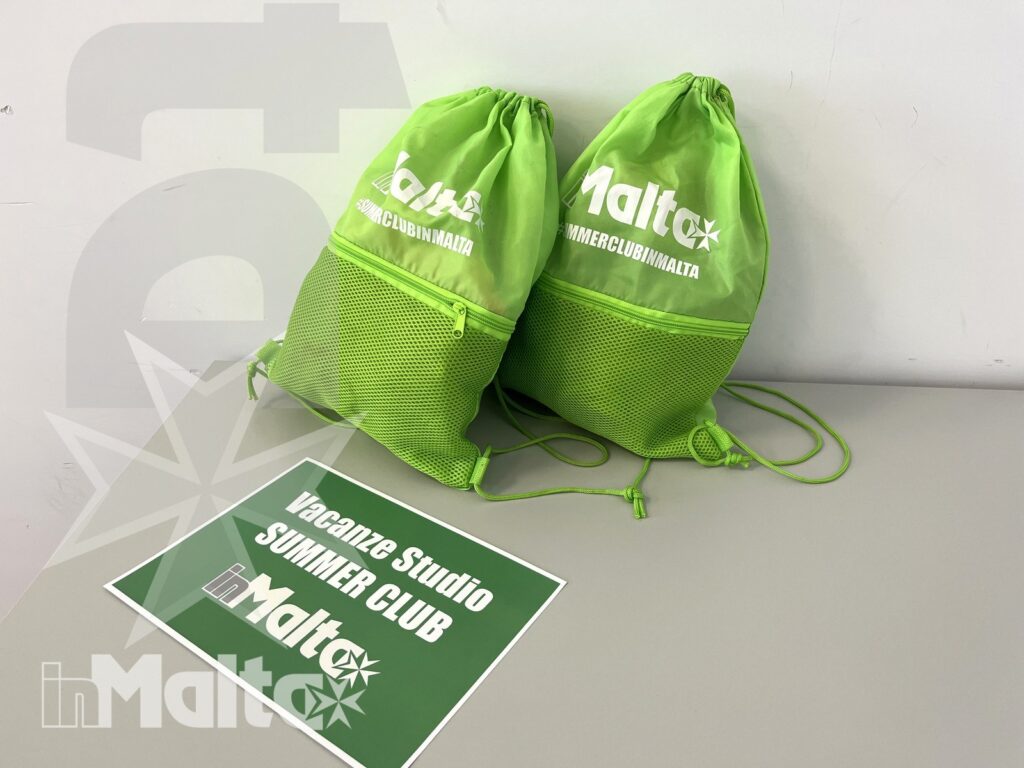 Kit del Summer Club per partecipanti alle vacanze studio Due sacche verdi brandizzate e un cartello del Summer Club presentano il merchandising destinato ai partecipanti a una vacanza studio a Malta.