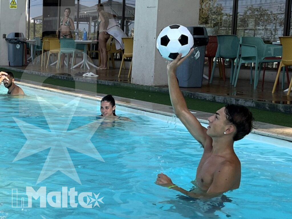 Studenti si passano una palla in piscina davanti alla struttura ricettiva, vivendo un'attività spontanea e conviviale.