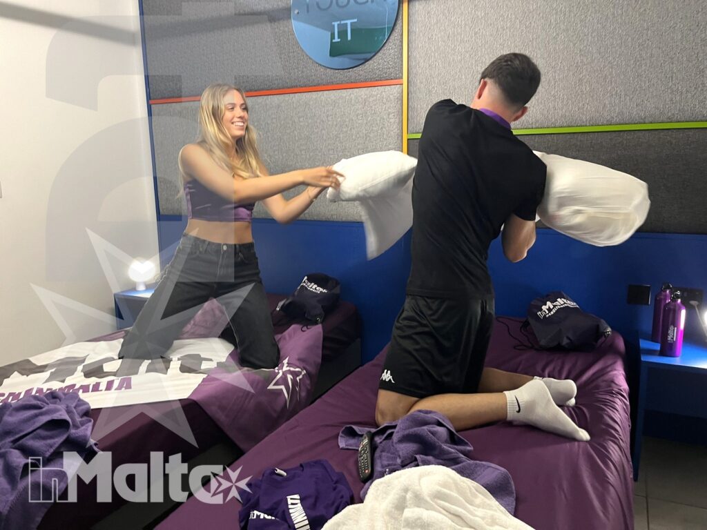 Studenti in vacanza studio giocano nella camera condivisa Due studenti giocano con i cuscini sui letti affiancati di una camera condivisa, in un momento spontaneo dell'alloggio.