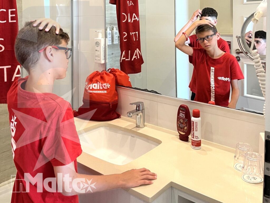 Uno studente si sistema i capelli davanti allo specchio del bagno, in un momento di routine quotidiana durante il soggiorno studio.