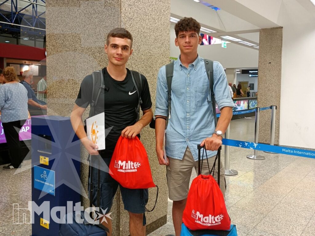Studenti inMalta nell'area arrivi dell'aeroporto Due studenti con trolley e borse personalizzate attendono nell'area arrivi dell'aeroporto, all'inizio del loro viaggio studio inMalta.
