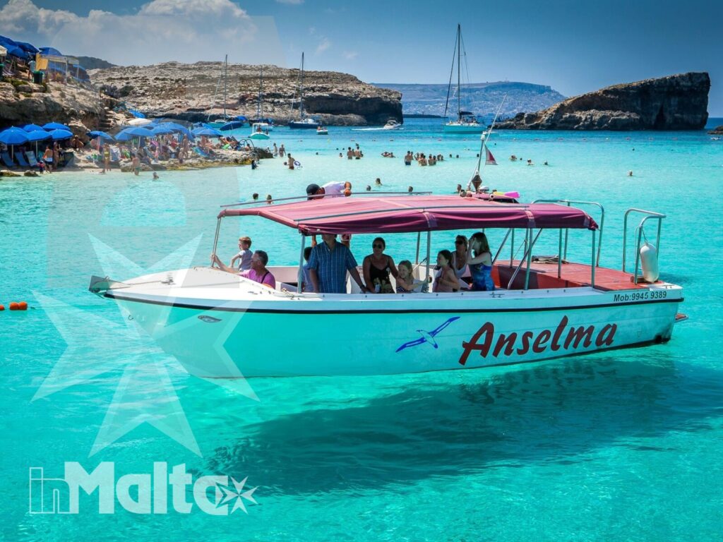 Barca turistica nella Blue Lagoon di Malta Barca turistica con passeggeri naviga nella Blue Lagoon, tra acque turchesi, spiaggia e scogliere di Malta.