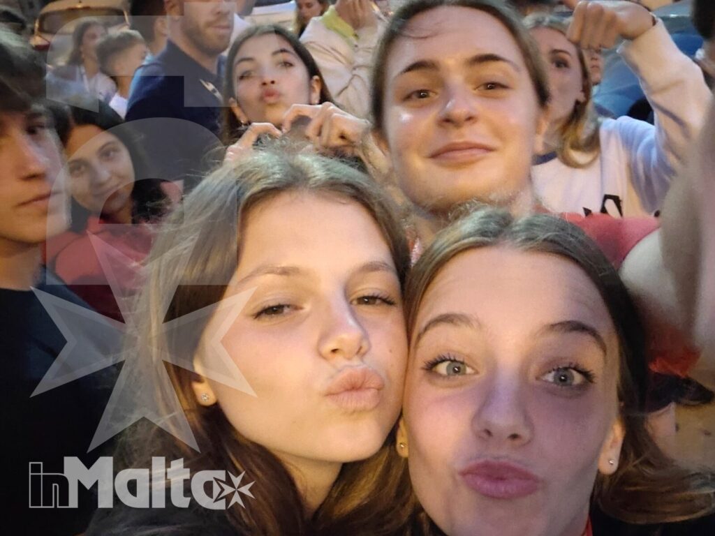 Studenti inMalta riuniti durante una serata di viaggio Gruppo numeroso di studenti sorridenti posa spontaneamente all'aperto durante una serata conviviale a Malta.