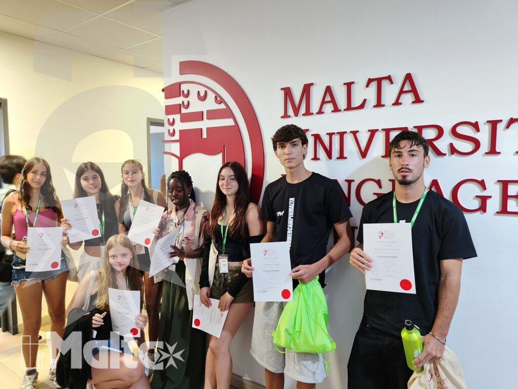 Studenti inMalta celebrano la conclusione del percorso linguistico Gruppo internazionale di studenti sorride mostrando i certificati davanti alla Malta University Language School, al termine del percorso formativo.