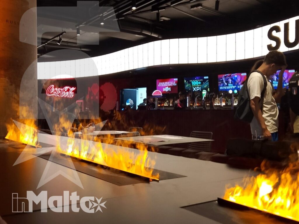 Ampia sala moderna con fiamme decorative, schermi luminosi e visitatori, parte dell'esperienza ricreativa durante un soggiorno studio.