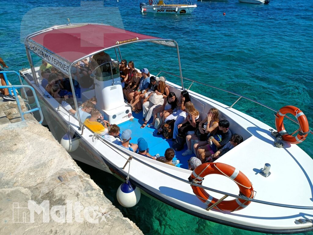Partenza in barca degli studenti da Hondoq Bay Gruppo di studenti prende posto su un motoscafo dal molo, pronto a partire per un'escursione nelle acque turchesi di Malta.