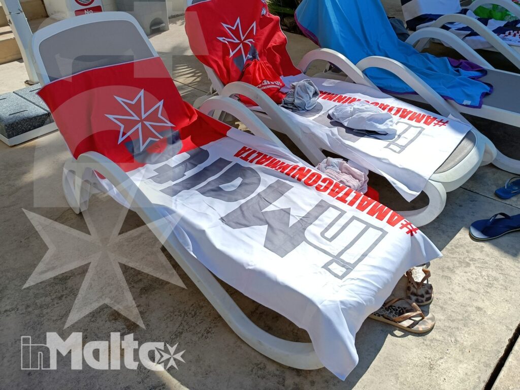 Lettini prendisole vuoti con asciugamani personalizzati, teli promozionali e sandali nell'area esterna del resort
