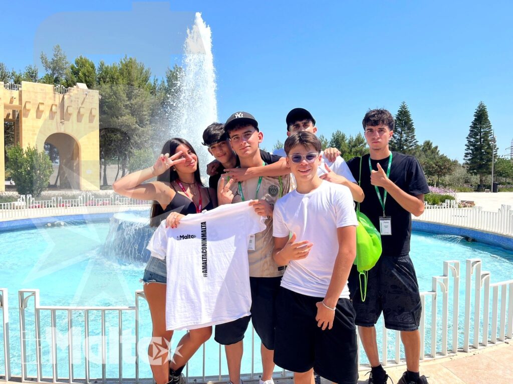 Sei studenti sorridenti posano davanti a una piscina con fontana durante un'attività estiva inMalta.