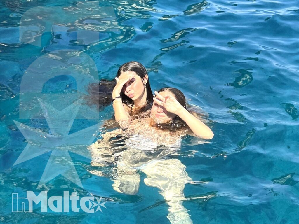 Due studentesse giocano in piscina e si sostengono in acqua, condividendo un momento spontaneo durante una vacanza studio a Malta.