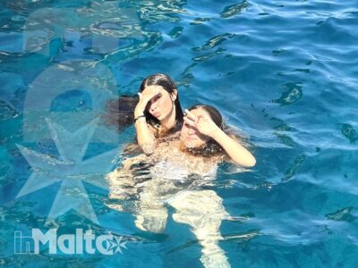 Due studentesse giocano in piscina e si sostengono in acqua, condividendo un momento spontaneo durante una vacanza studio a Malta.
