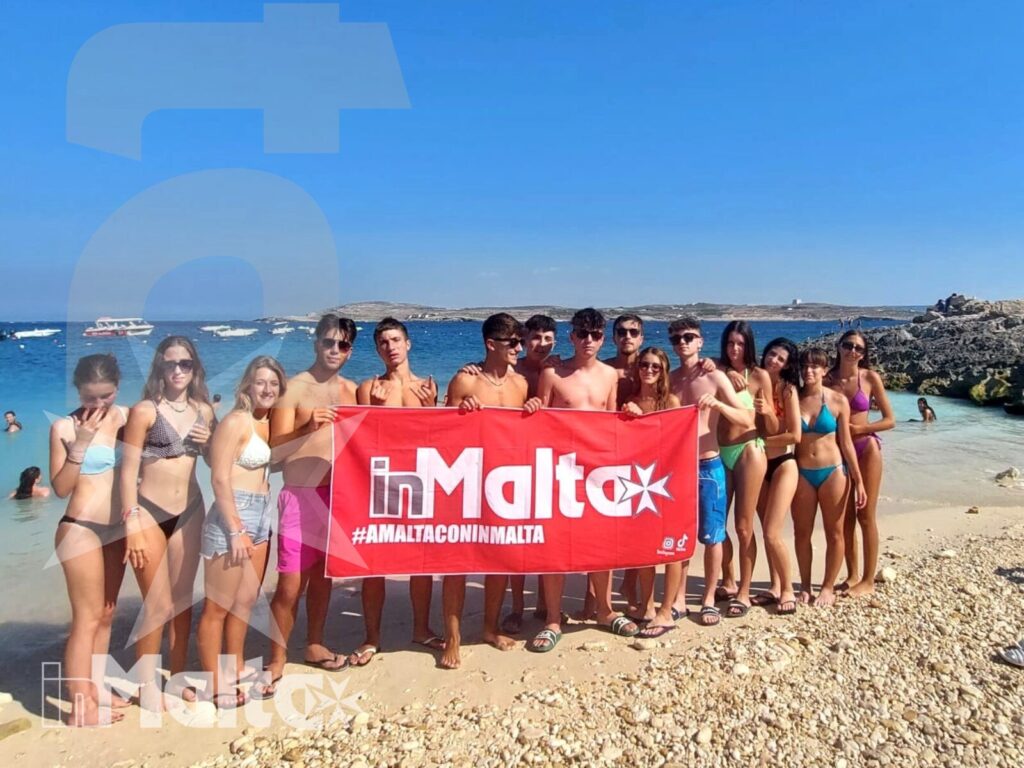 Studenti inMalta riuniti sulla spiaggia di Hondoq Bay Gruppo numeroso di studenti posa con uno striscione sulla spiaggia rocciosa di Hondoq Bay, durante una giornata al mare a Malta.