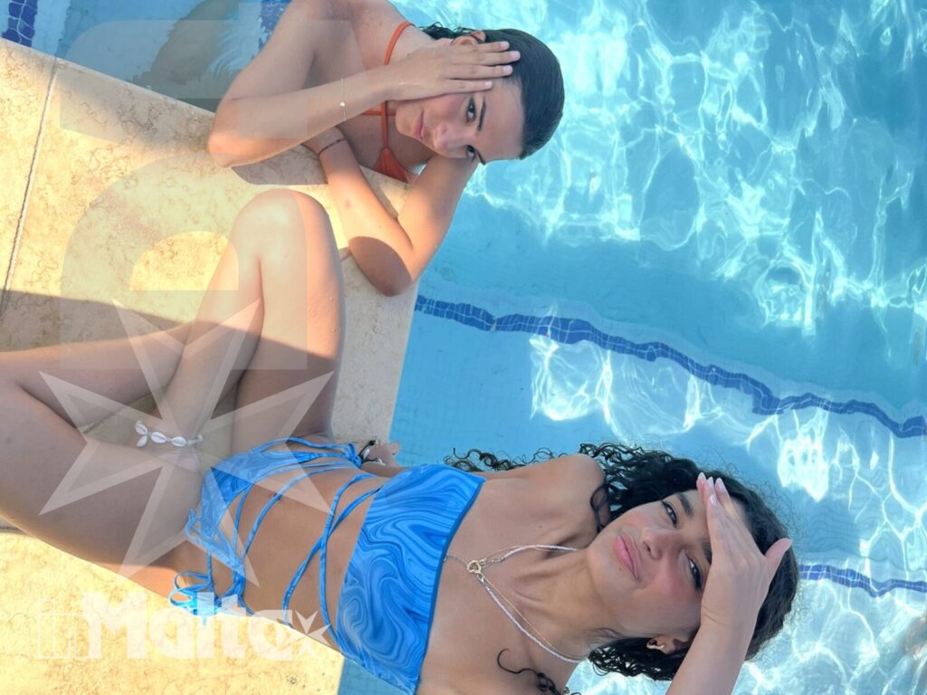 Due studentesse si rilassano sdraiate sul bordo illuminato della piscina, in un momento informale del soggiorno inMalta.