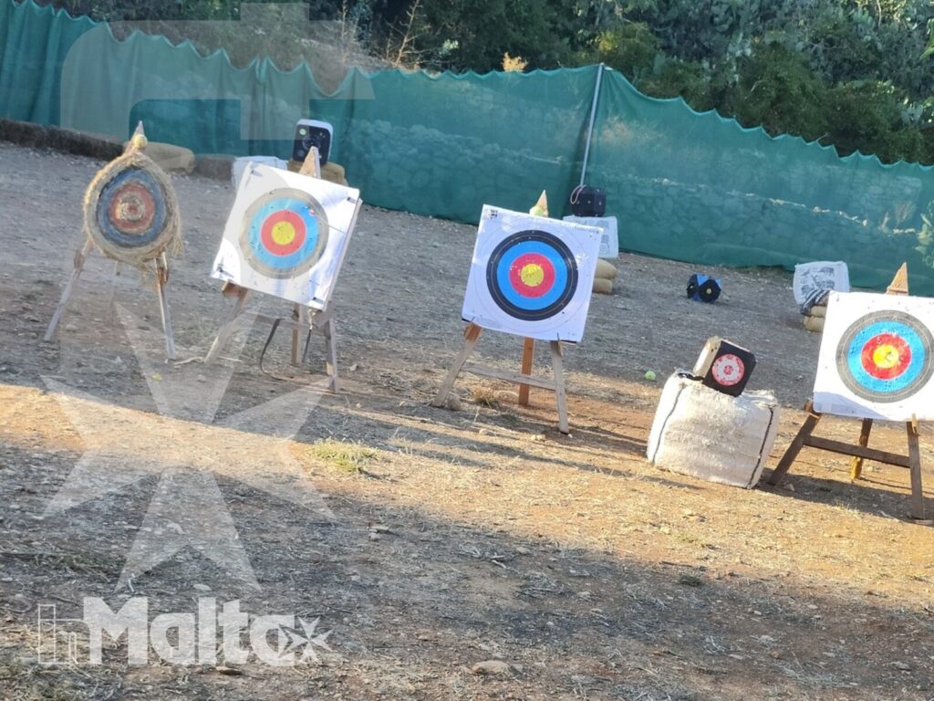 Bersagli circolari multicolori allineati in un campo di tiro con l'arco, circondati dalla vegetazione mediterranea.