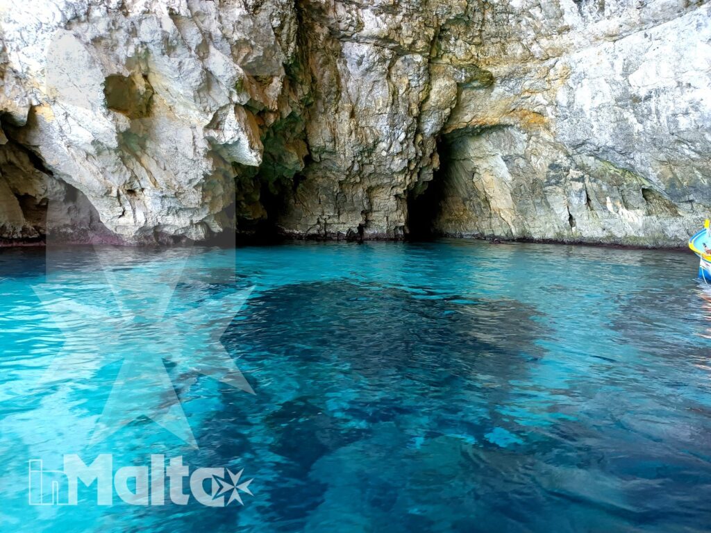 Acque turchesi e pareti rocciose illuminano l'interno di una grotta marina visitata durante un'escursione sulla costa maltese.