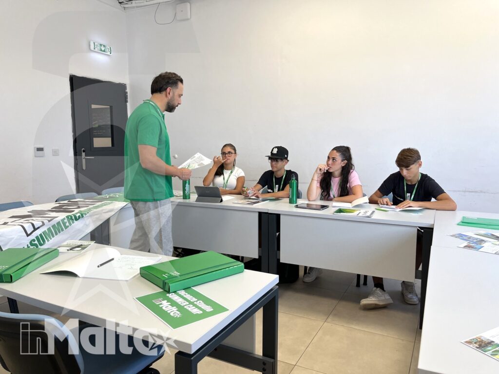 Formatore e studenti durante un incontro didattico a Malta Un formatore distribuisce cartelline e materiali a studenti seduti durante un incontro di orientamento in aula.